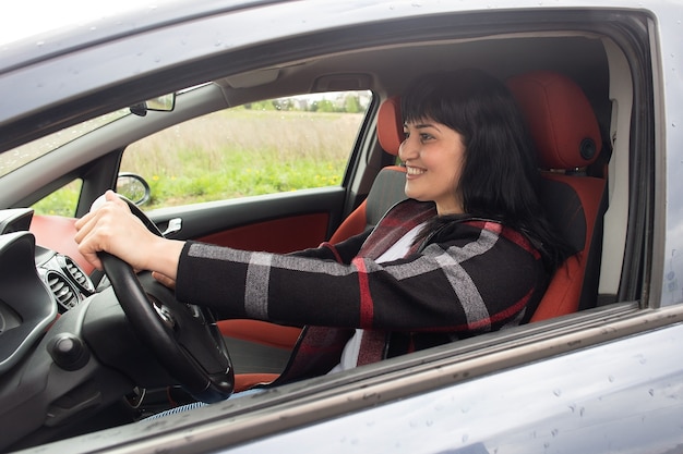 La hermosa mujer feliz en el coche