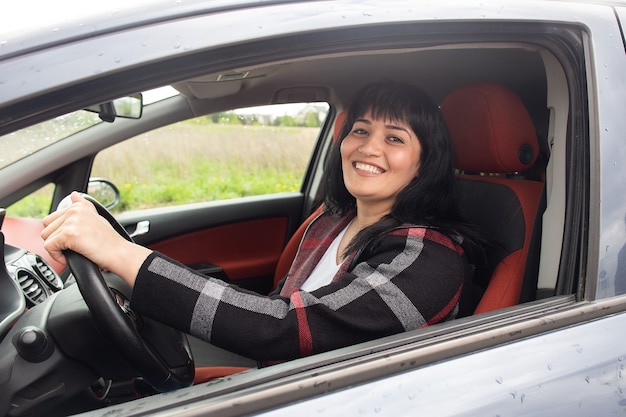 La hermosa mujer feliz en el coche