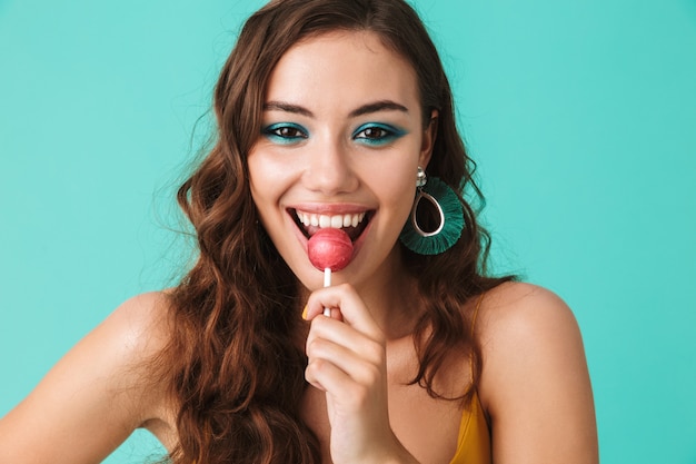 Hermosa mujer feliz con mirada juguetona sonriendo y comiendo piruletas