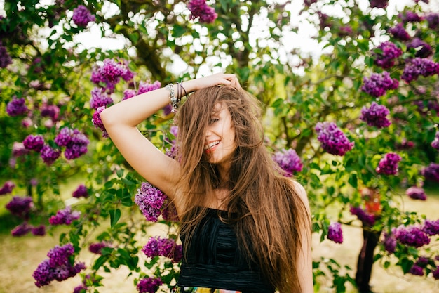 Foto hermosa mujer feliz con el pelo largo en el jardín con flores