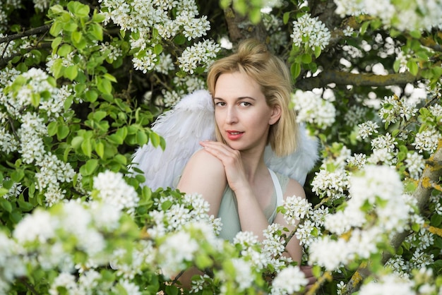 Hermosa mujer femenina con alas blancas con flores blancas de primavera