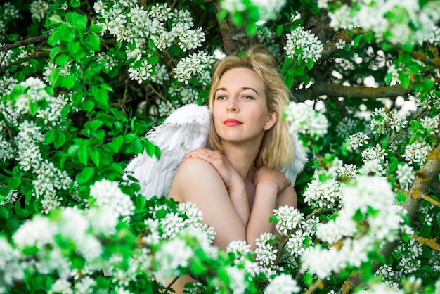 Hermosa mujer femenina con alas blancas con flores blancas de primavera