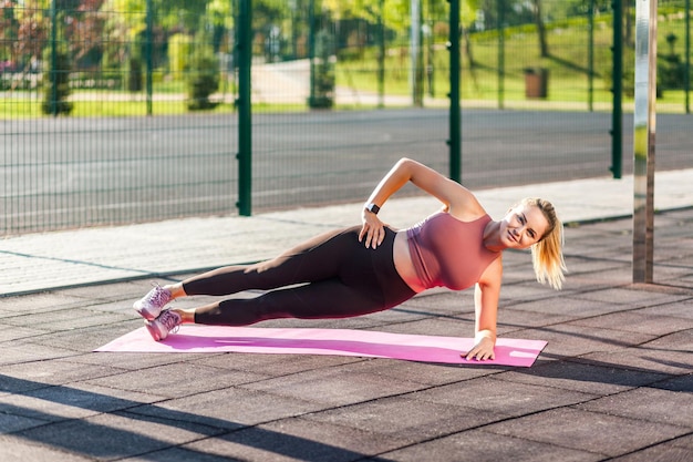 Hermosa mujer fitness con pantalones ajustados entrenando en un día de  verano al aire libre, haciendo