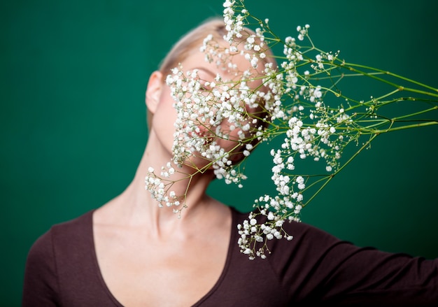 Hermosa mujer con flor de gypsophila en escena verde