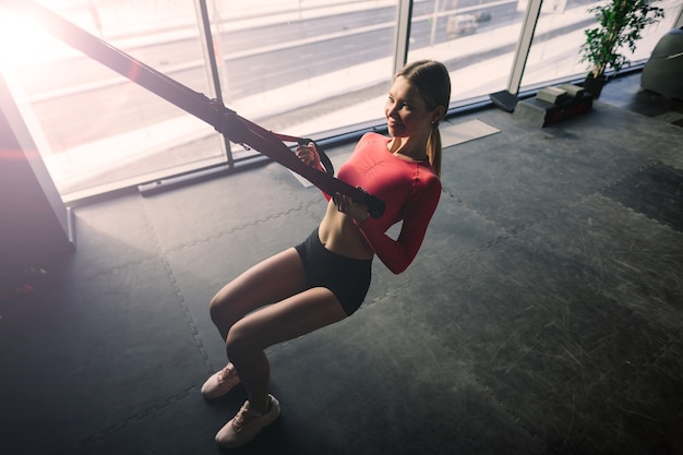 Hermosa mujer en forma muscular haciendo ejercicio, construyendo músculos en el gimnasio