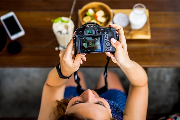 Hermosa mujer fotografía su comida en la cámara.