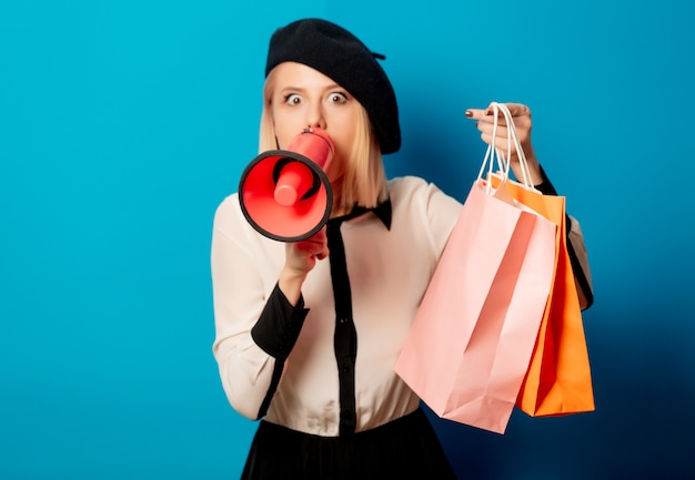 Hermosa mujer francesa en boina con bolsas de compras y altavoz