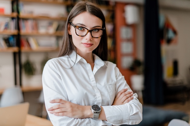 Hermosa mujer con gafas y camisa en la oficina