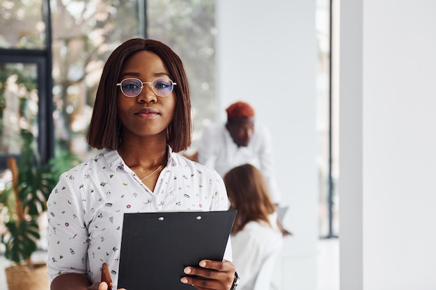 Hermosa mujer con gafas frente a sus colegas Grupo de empresarios afroamericanos que trabajan juntos en la oficina