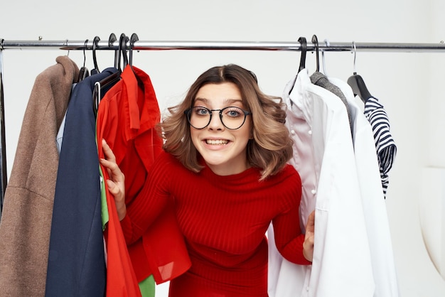 Hermosa mujer con gafas probándose ropa tienda adicta a las compras fondo aislado