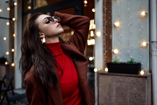 Hermosa mujer con gafas de sol arreglando el cabello en la calle