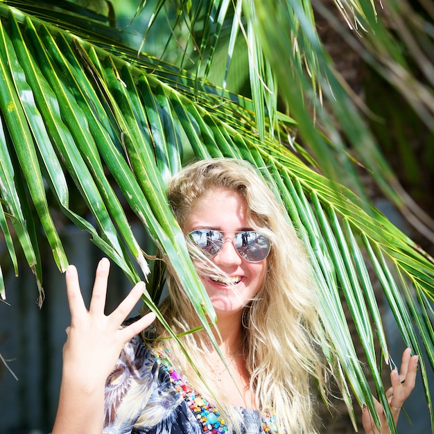 Hermosa mujer en gafas de sol con palmera tropical