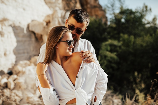 Hermosa mujer con gafas de sol se relaja en los brazos de su hombre