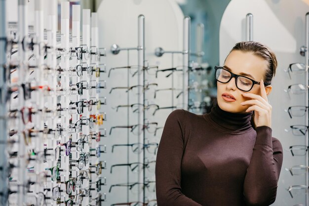 Hermosa mujer con gafas en la tienda de óptica Corrección de la vista Óptica Oftalmología