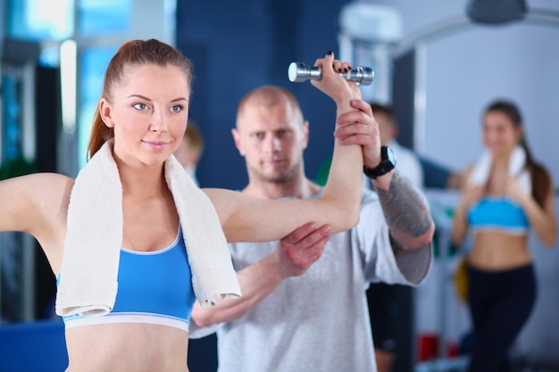 Hermosa mujer en el gimnasio haciendo ejercicio con su entrenador