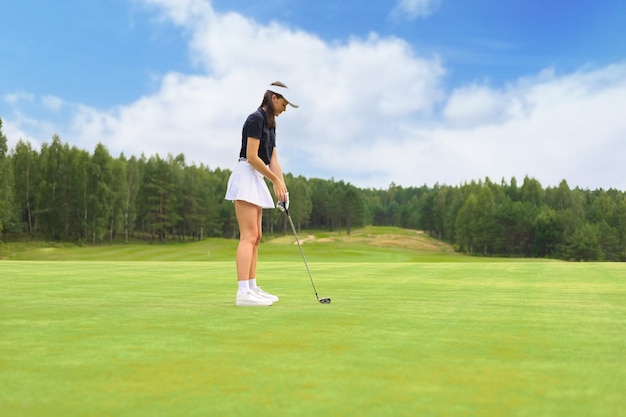 Hermosa mujer golfista se prepara para disparar a la pelota en el campo de golf verde.