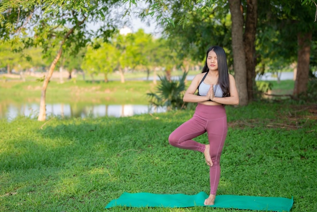 Hermosa mujer gorda asiática juega yoga en el parque Necesita adelgazar el cuerpo