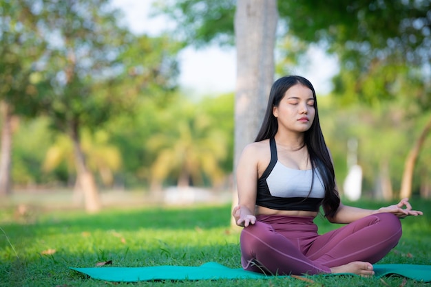 Hermosa mujer gorda asiática juega yoga en el parque Necesita adelgazar el cuerpo