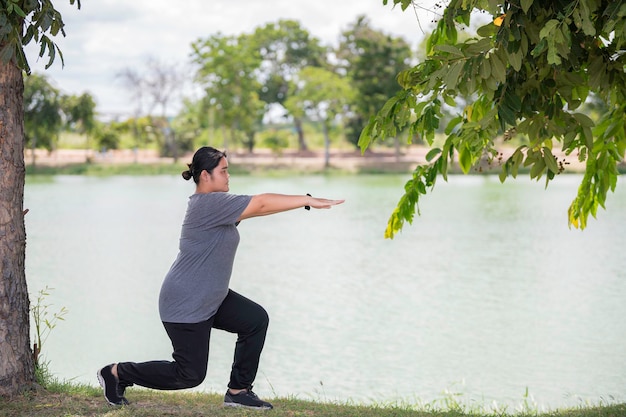 Hermosa mujer gorda asiática juega yoga en el parque Necesita adelgazar el cuerpo