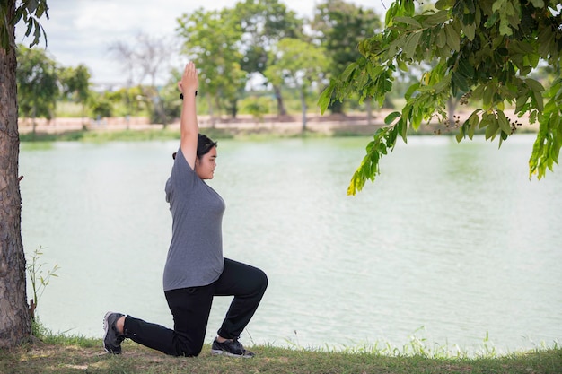 Hermosa mujer gorda asiática juega yoga en el parque Necesita adelgazar el cuerpo