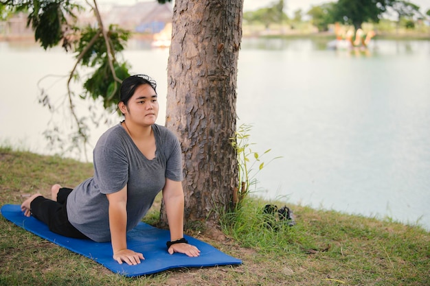 Hermosa mujer gorda asiática juega yoga en el parque Necesita adelgazar el cuerpo