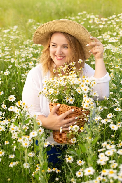 hermosa mujer gorda en un campo con margaritas y un sombrero