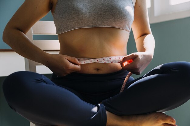 Foto hermosa mujer gorda con cinta métrica. usa su mano para exprimir el exceso de grasa que está aislado en un fondo blanco. quiere perder peso, el concepto de cirugía y descomponer la grasa bajo el