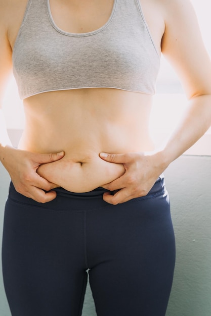 Foto hermosa mujer gorda con cinta métrica. usa su mano para exprimir el exceso de grasa que está aislado en un fondo blanco. quiere perder peso, el concepto de cirugía y descomponer la grasa bajo el