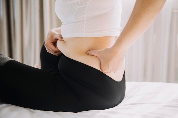 Hermosa mujer gorda con cinta métrica. Usa su mano para exprimir el exceso de grasa que está aislado en un fondo blanco. Quiere perder peso, el concepto de cirugía y descomponer la grasa bajo el