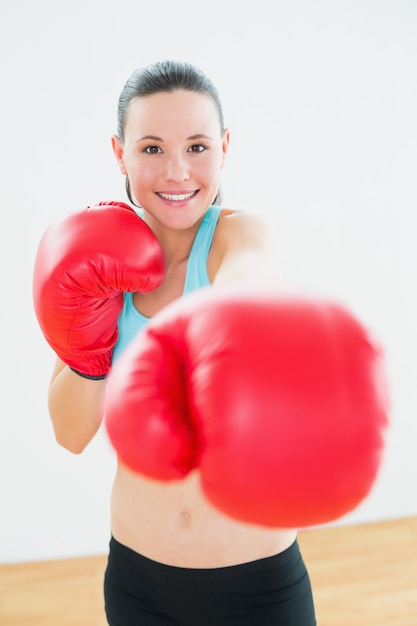 Hermosa mujer en guantes de boxeo rojos en el gimnasio