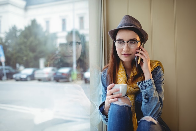 Hermosa mujer hablando por celular en el café