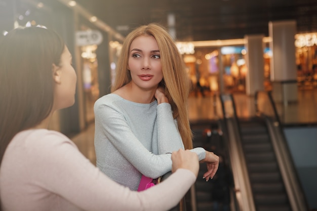 Hermosa mujer hablando con su amiga en el centro comercial