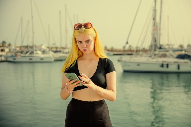 Hermosa mujer hablando por teléfono con el telón de fondo del mar azul y los yates