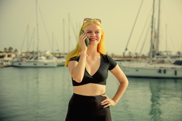 Hermosa mujer hablando por teléfono con el telón de fondo del mar azul y los yates