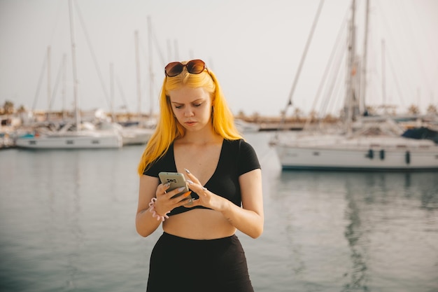 Hermosa mujer hablando por teléfono con el telón de fondo del mar azul y los yates