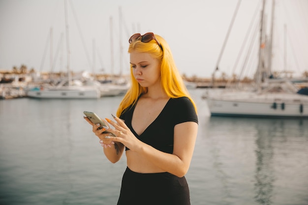 Hermosa mujer hablando por teléfono con el telón de fondo del mar azul y los yates