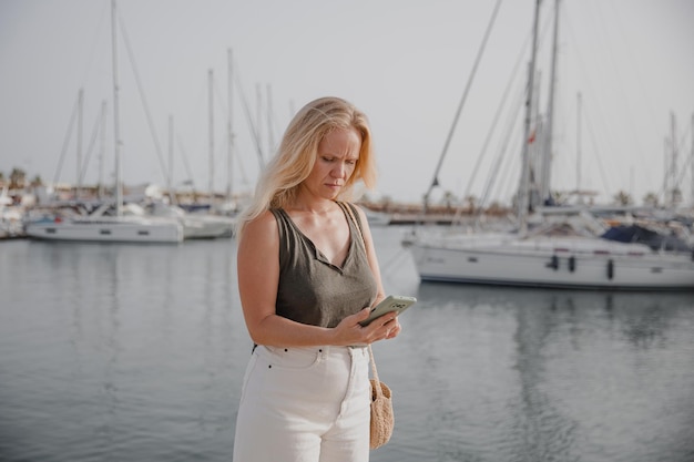 Hermosa mujer hablando por teléfono con el telón de fondo del mar azul y los yates