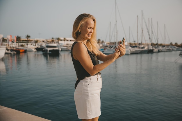 Hermosa mujer hablando por teléfono con el telón de fondo del mar azul y los yates