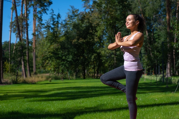 Hermosa mujer haciendo asanas al aire libre - Yoga Balance Vriksha-Asana The Tree Pose