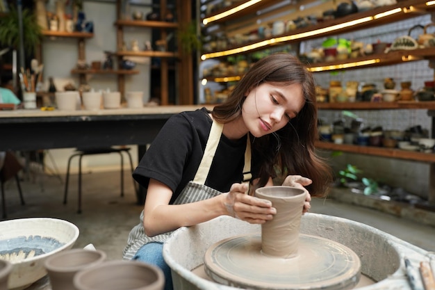 Hermosa mujer haciendo cerámica en las manos de la rueda mujer de primer plano en el hobby de negocios independientes