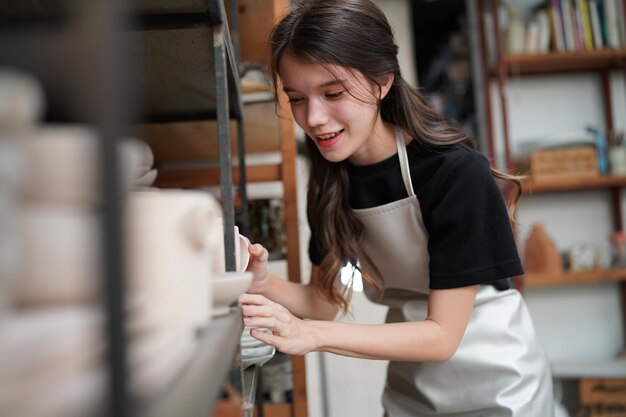 Hermosa mujer haciendo cerámica en las manos de la rueda mujer de primer plano en el hobby de negocios independientes