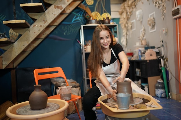 Hermosa mujer haciendo cerámica en las manos de la rueda mujer de primer plano en el hobby de negocios independientes