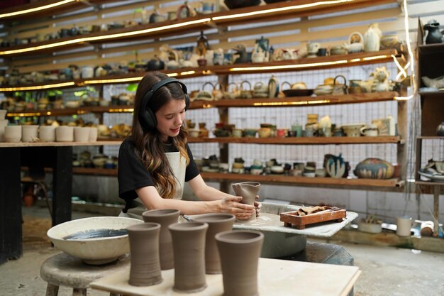 Foto hermosa mujer haciendo cerámica en las manos de la rueda mujer de primer plano en el hobby de negocios independientes