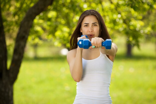 Hermosa mujer haciendo ejercicio al aire libre. Alegre chica delgada haciendo ejercicio en el parque en verano