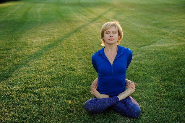 Hermosa mujer haciendo ejercicios de yoga en el parque