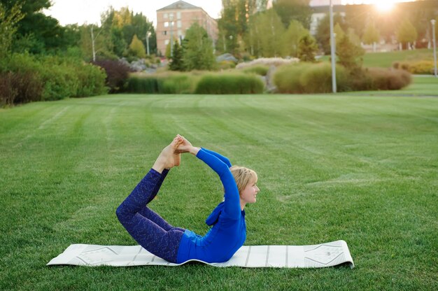 Hermosa mujer haciendo ejercicios de yoga en el parque