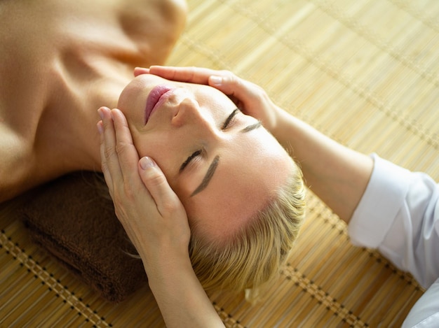 Hermosa mujer haciendo masaje facial en un salón de spa