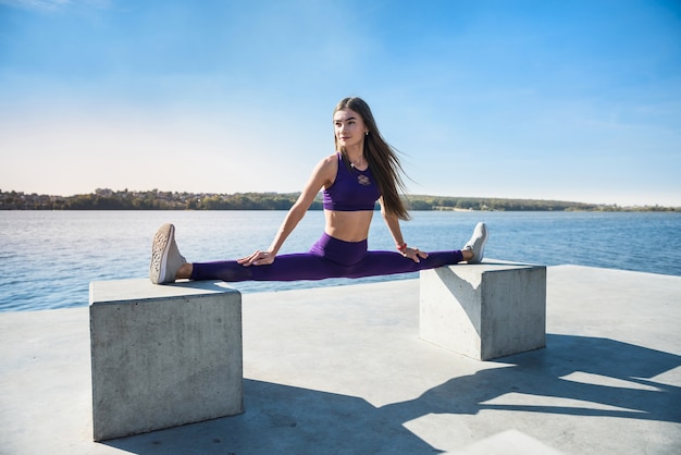 Hermosa mujer haciendo split en un cálido día de verano. concepto de estilo de vida activo deportivo