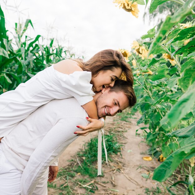 Hermosa mujer hermosa y elegante pareja masculina, rústica en un campo de girasoles besos, tiernos