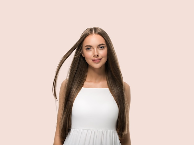 Hermosa mujer con hermoso cabello largo y liso en vestido blanco sobre fondo de color